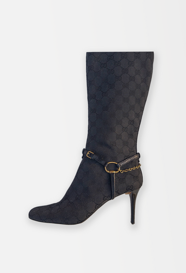 Gucci Tom Ford knee boots in black GG monogram canvas with with leather harness straps, anchored by gold-tone horse bit hardware and fine chain - side view