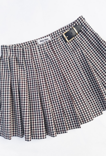 Miu Miu pleated skirt in gingham pattern with  two gold-tone buckled leather tabs at the waist - angled view